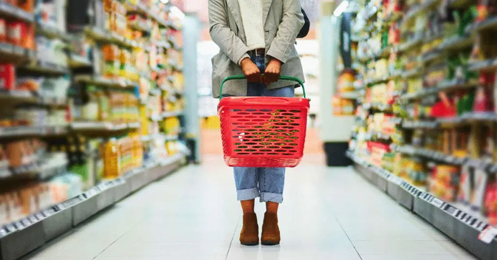 a woman holding a grocery basket at the grocery store. How inflation affects the economy.